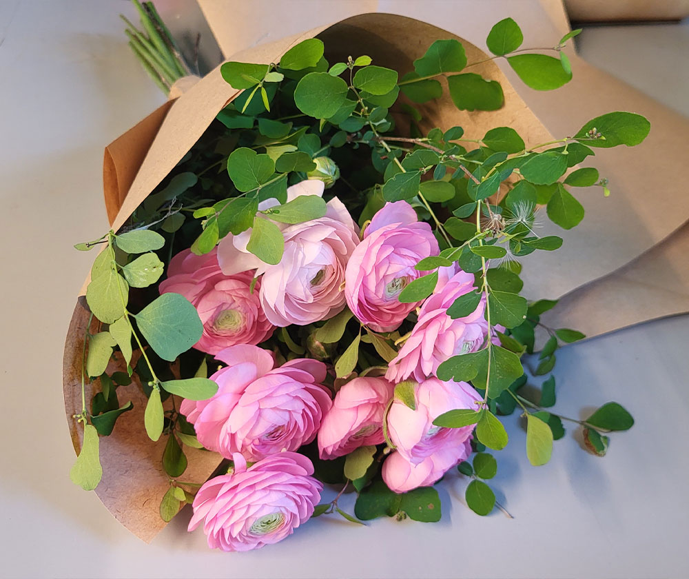 Ranunculus bouquet in vase with white ribbon
